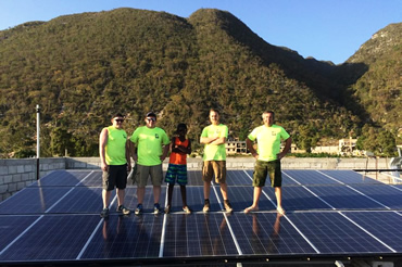 SLP Team standing on solar panels with mountains in background