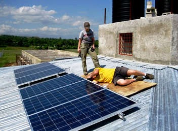 Photo of SLP team installing solar panel on roof