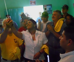 First Lady Rosa Elena de Lobo turns on the first electric solar-powered light in the one-room school in El Trapiche.