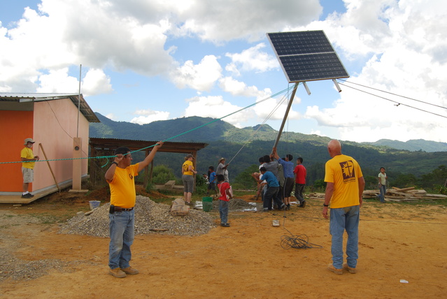 Mexico - Team hoisting pole-mounted solar array with view